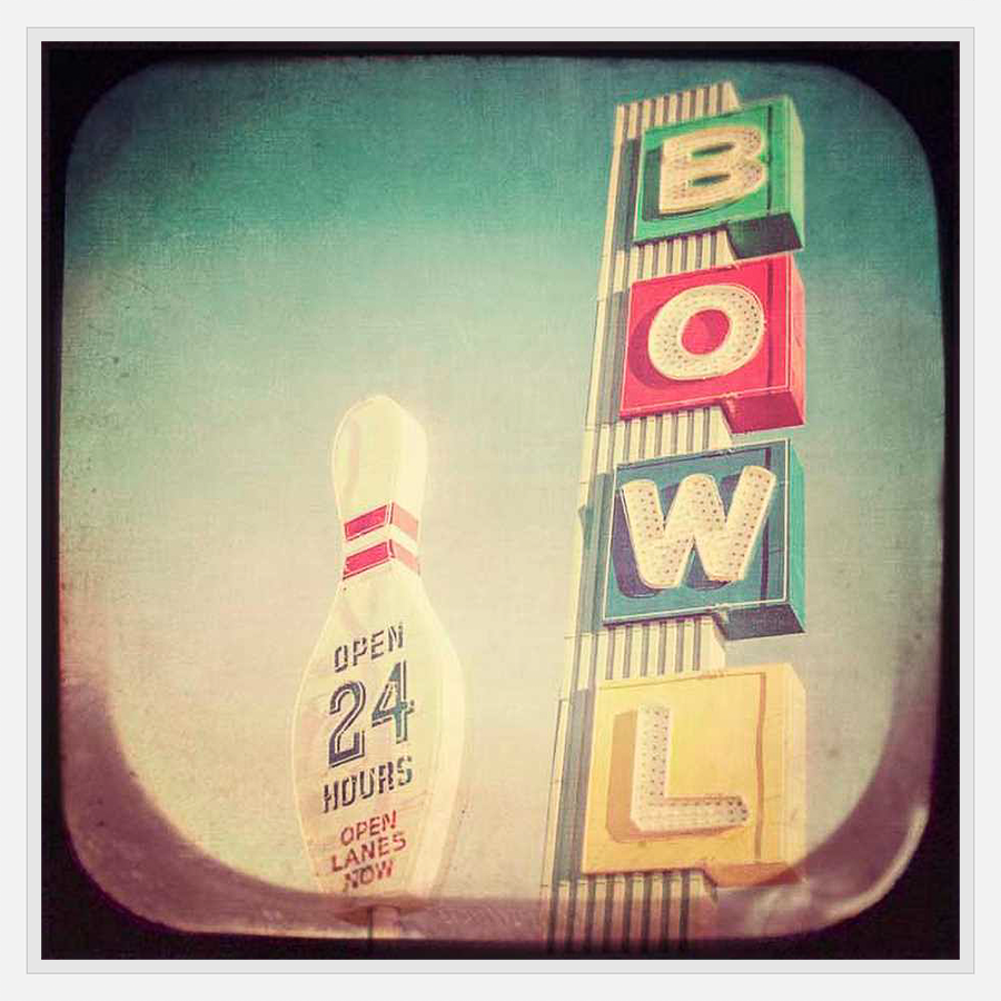 This vintage-inspired artwork captures the nostalgic charm of a classic bowling alley. The image features a bowling pin and a vibrant "BOWL" sign set against a retro sky, evoking a sense of timeless fun and Americana. It's a perfect piece for adding a touch of retro flair to any space.